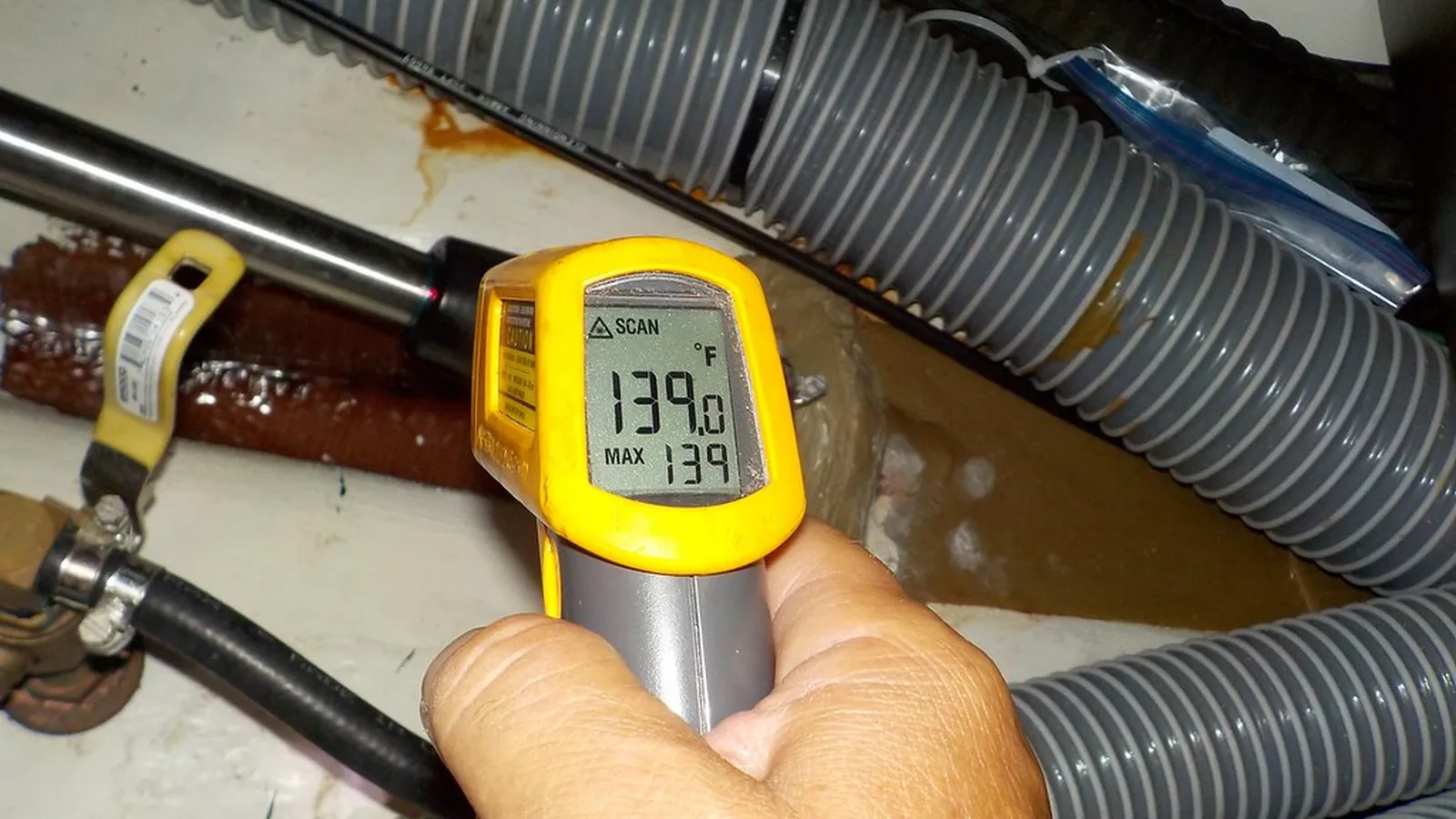 Technician checking seal and piping temperatures with an infrared thermometer on a pump system