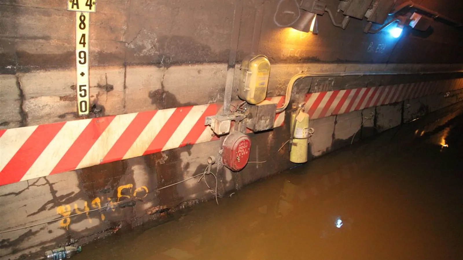 Water drainage tunnel with yellow pressure lines along the wall