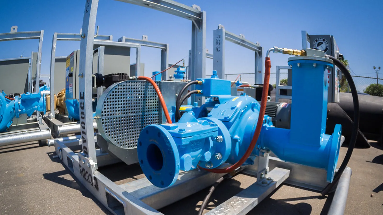 Skid-mounted blue pump sets with guard and pipework outdoors